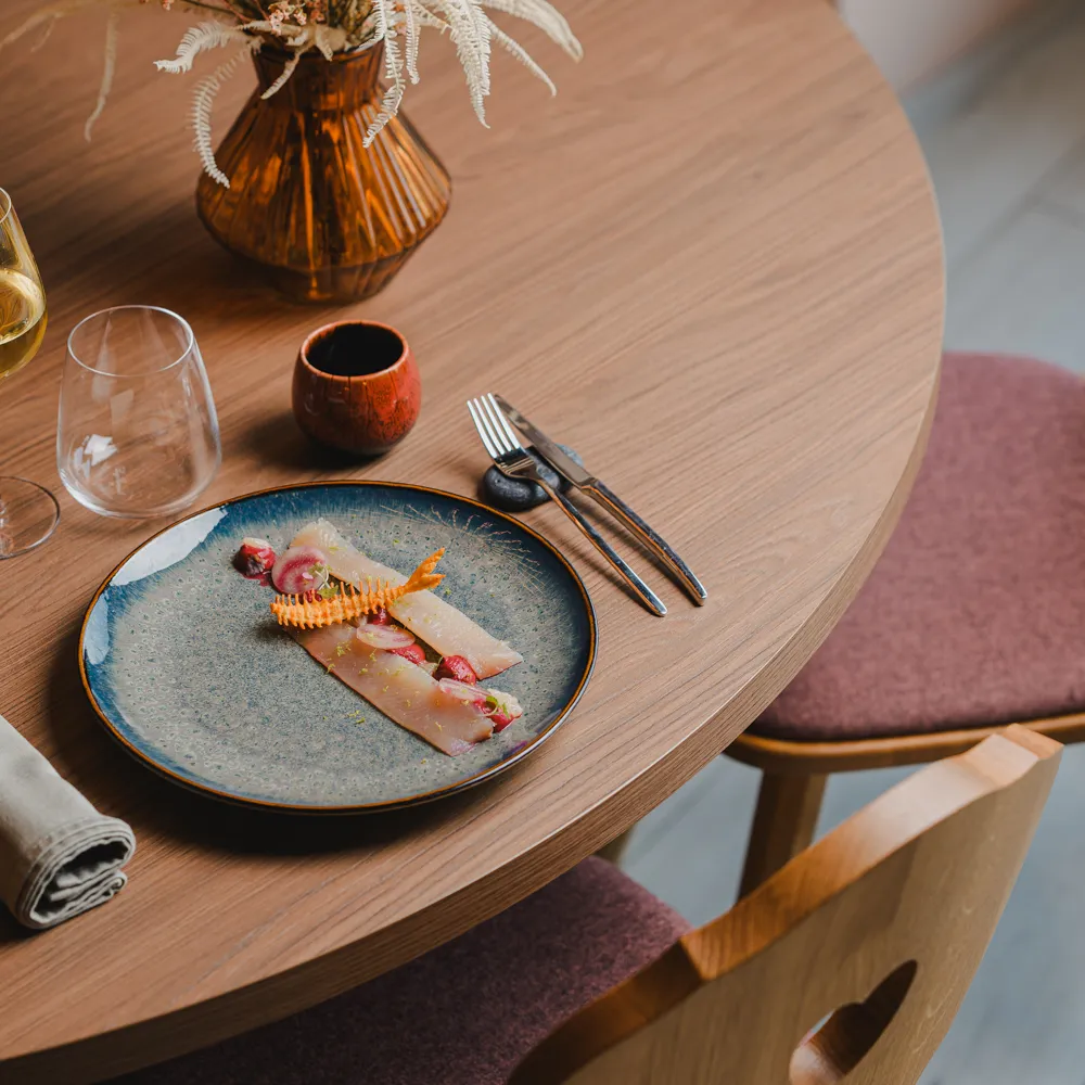 A plated dish and a glass of white wine on a wooden table at L'Alambic