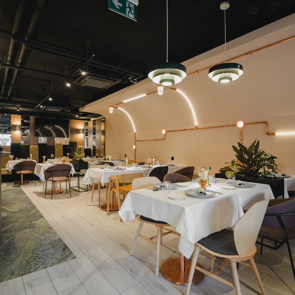 L'Alambic dining room with dressed tables, armchairs and copper lighting