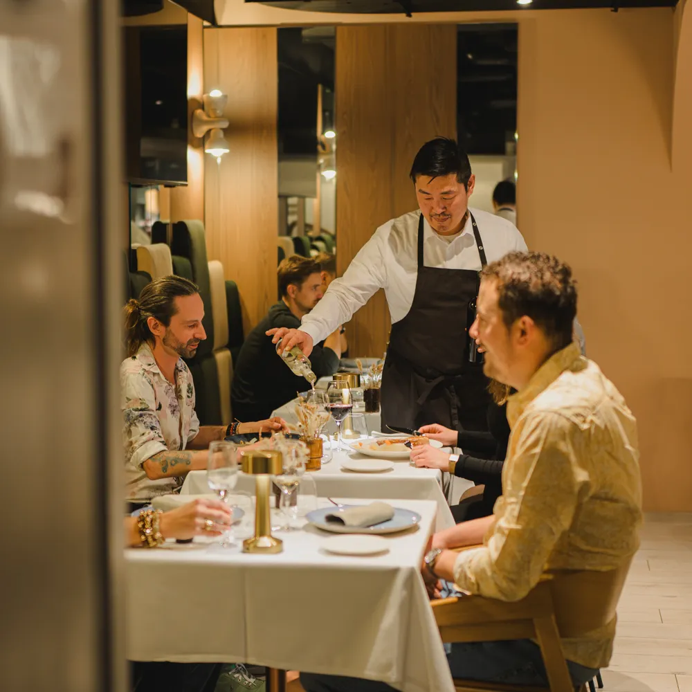 Wine being served to guests at a table in L'Alambic's dining room